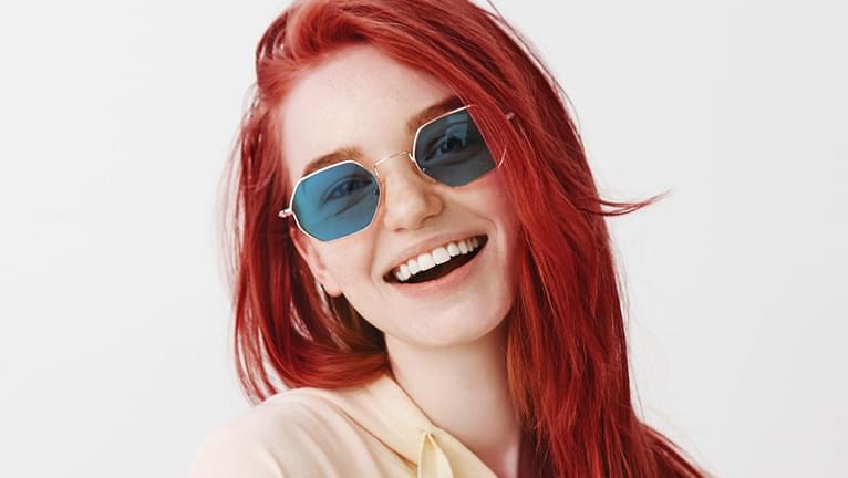 Blue tinted sunglasses are stylish when paired with red hair.