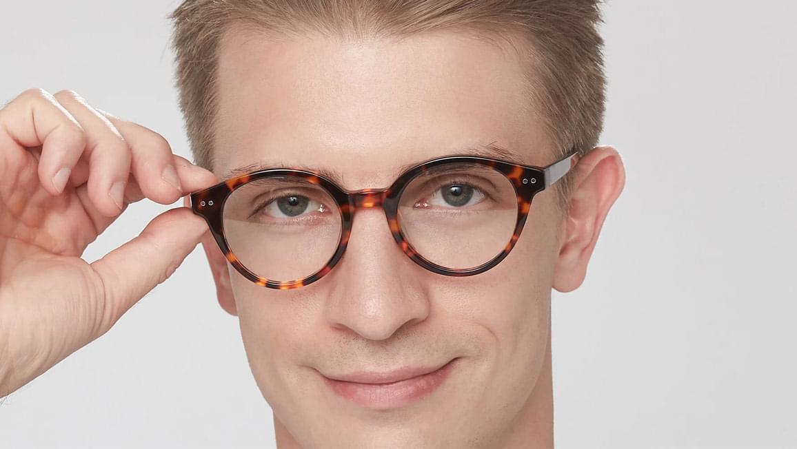 A man showing off round tortoise shell pattern glasses.