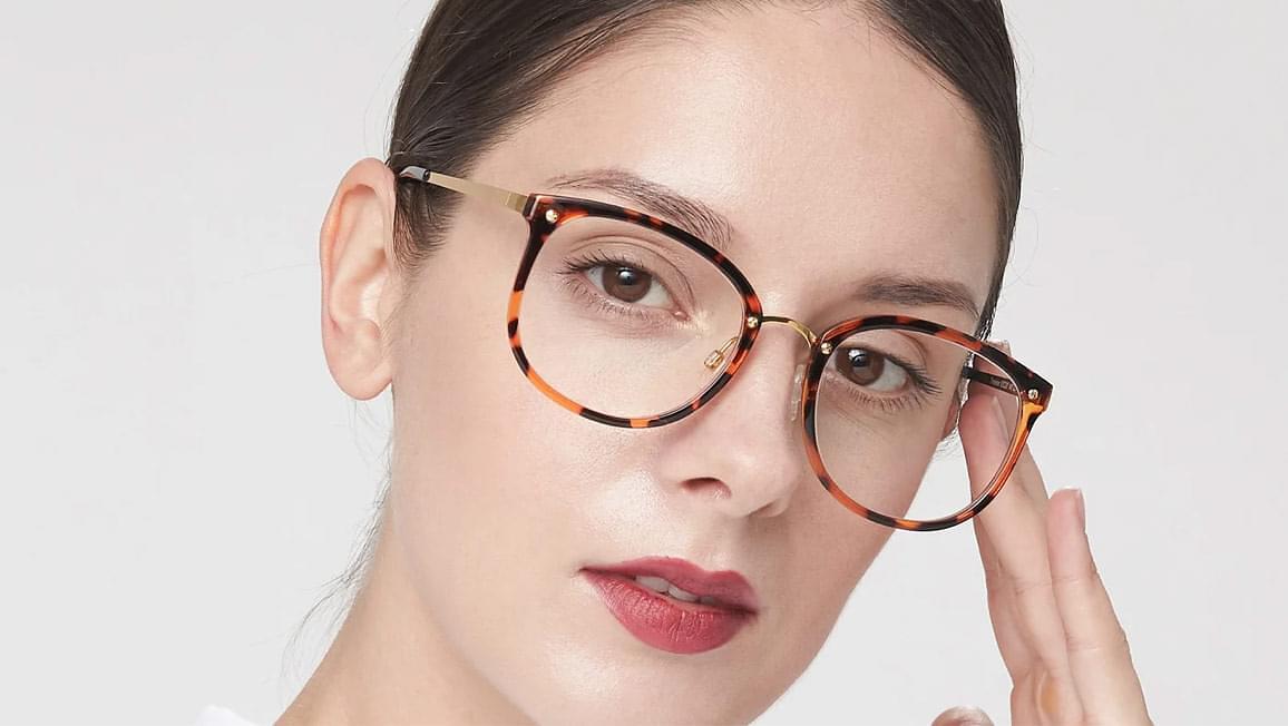 A woman showing off horn rimmed tortoise shell pattern glasses.