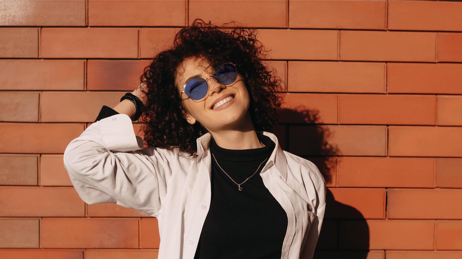 Young short haired woman tourist in sunglasses using laptop while sitting  on fitness mat near Stock Photo by LightFieldStudios